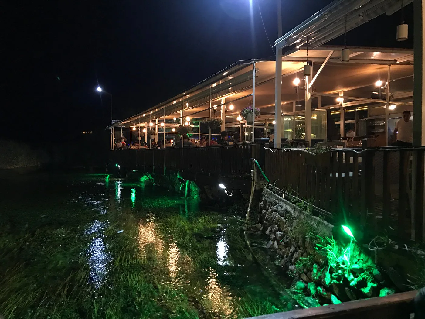 Olta Restaurant’ın akşam ışıklarıyla aydınlanan terası ve Azmak’taki yansımaları